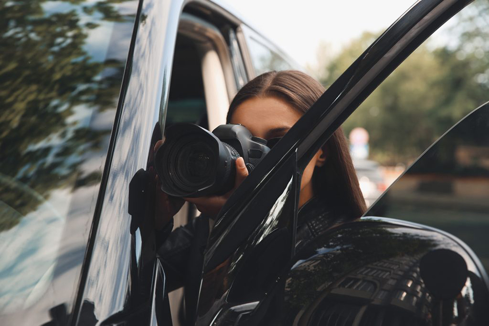 Egy nő fényképet készít az autója ajtaja mögül.
